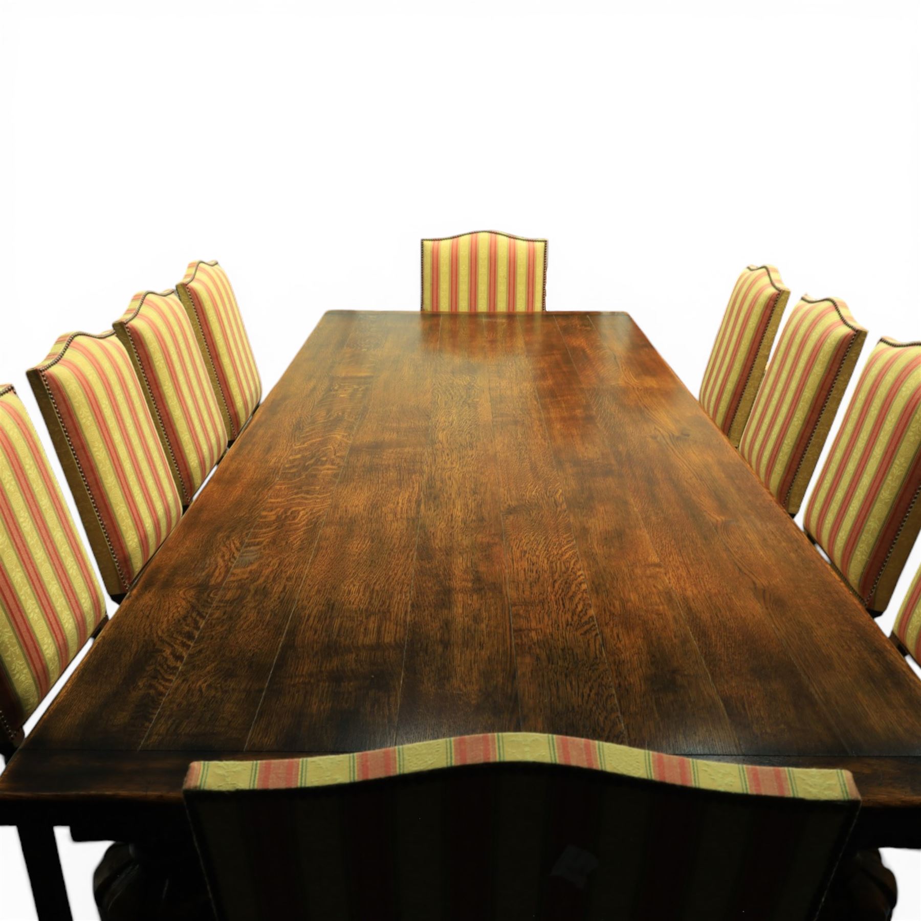 Royal Oak Furniture Co - Jacobean style oak dining table with suite of ten oak high back dining chairs (8+2), rectangular plank top dining table with moulded edge above carved frieze, raised on bulbous turned supports united by stretchers, together with a set of oak framed high back dining chairs including two carvers, upholstered in striped fabric with studded borders, on turned supports united by stretchers 