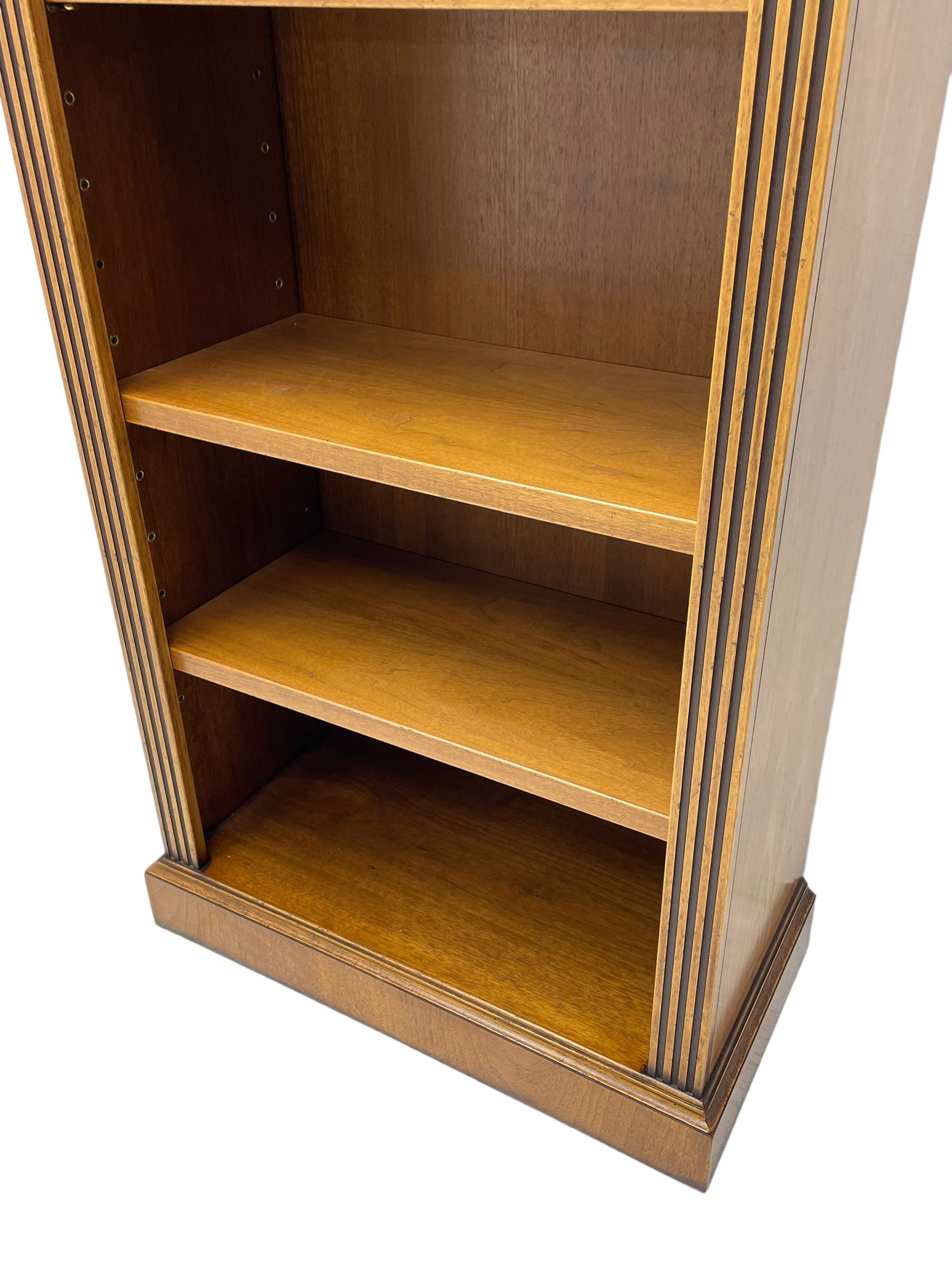 Georgian design walnut open bookcase, projecting cornice over figured banded frieze flanked by roundels, fitted with six adjustable shelves with flanking fluted uprights, on skirted base