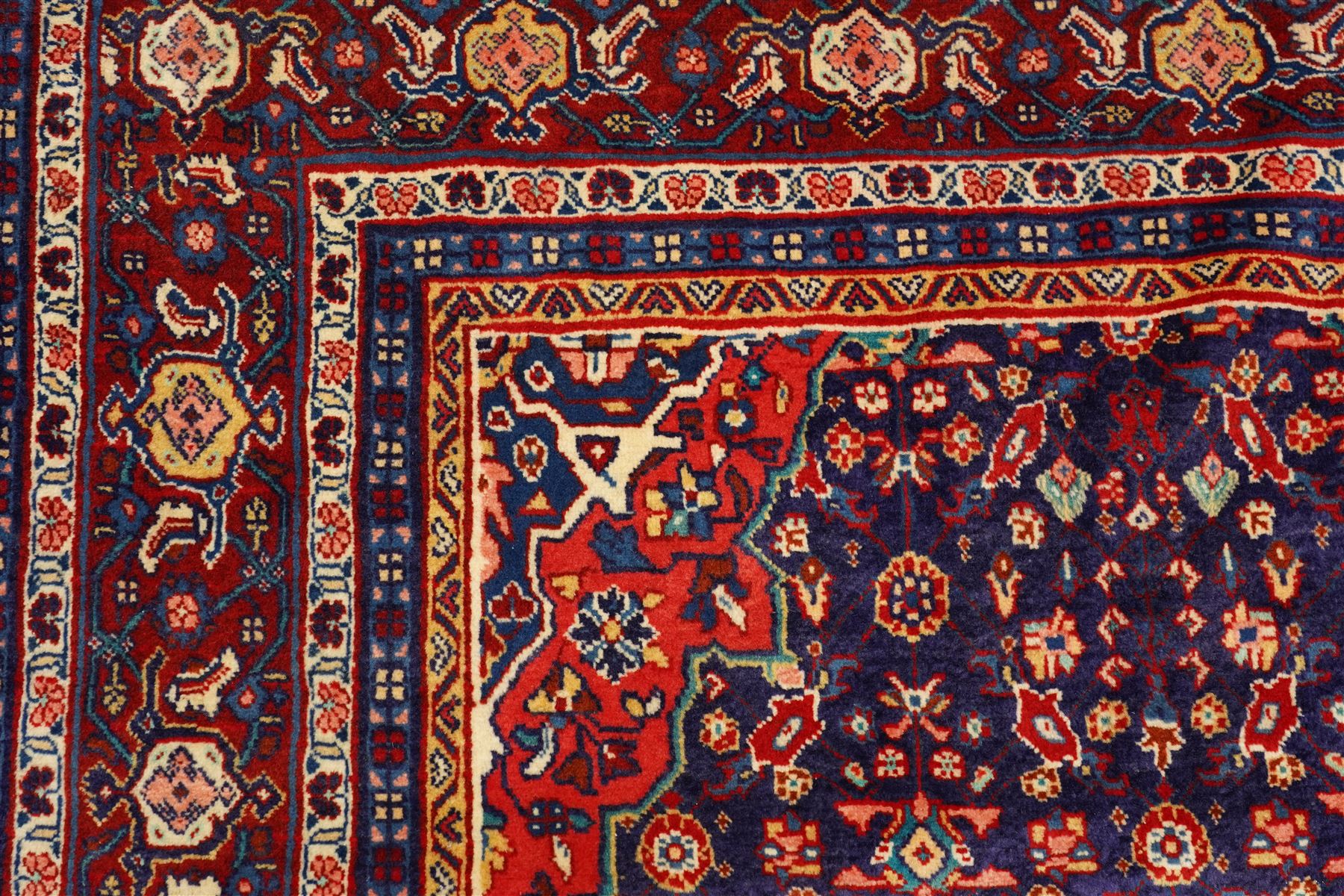 West Persian Mahal hand-knotted carpet, indigo field with central stylized angular medallion issuing an all-over Herati-inspired lattice of floral sprays, rosettes and geometric vinery in tone soft madder red, ivory and soft blue, principal border decorated with stylized palmettes, and angular vine motifs, flanked by multiple guard borders, with cotton fringe ends 