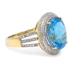14ct gold Swiss blue topaz and diamond cluster ring, single oval cut topaz of approx 8.85 carat, surrounded by two rows of single cut diamonds and split diamond set shoulders
