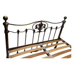 Victorian design king size brass bed frame, featuring an arched headboard and footboard with intricate cast floral and scrollwork centre motifs, flanked by cylindrical supports with ball finials and decorative collars, raised on rounded feet, with a slatted wooden base