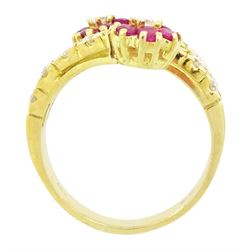 18ct gold ruby and diamond flower head crossover ring, two flowers each set with a single round brilliant cut diamond and six rubies, to diamond set stems and spaced by a row of nine diamonds, stamped 750, total diamond weight approx 0.55 carat