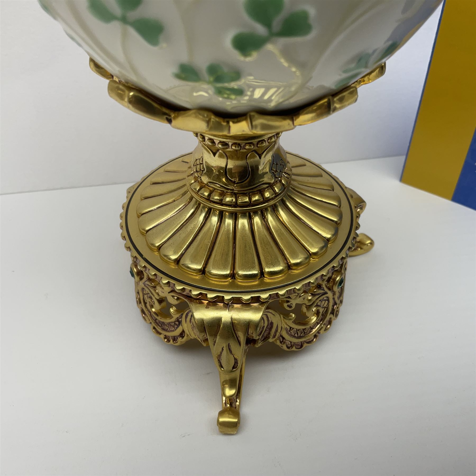 Franklin Mint The Emerald Isle Collector Egg, the egg decorated with embossed shamrocks upon a cream ground, with a gilded shamrock finial, accents and openwork door, opening to reveal a miniature landscape scene, upon three gilded feet set with green paste stones, with certificate of authenticity H23cm, 