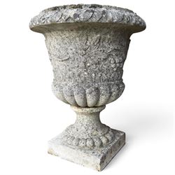 Set of four weathered composite stone urns of campana form, the everted leaf-moulded rolled rim over a body decorated with scrolling fruiting grapevines in relief, over a gadrooned underbelly and waisted socle, lobed collar on square base