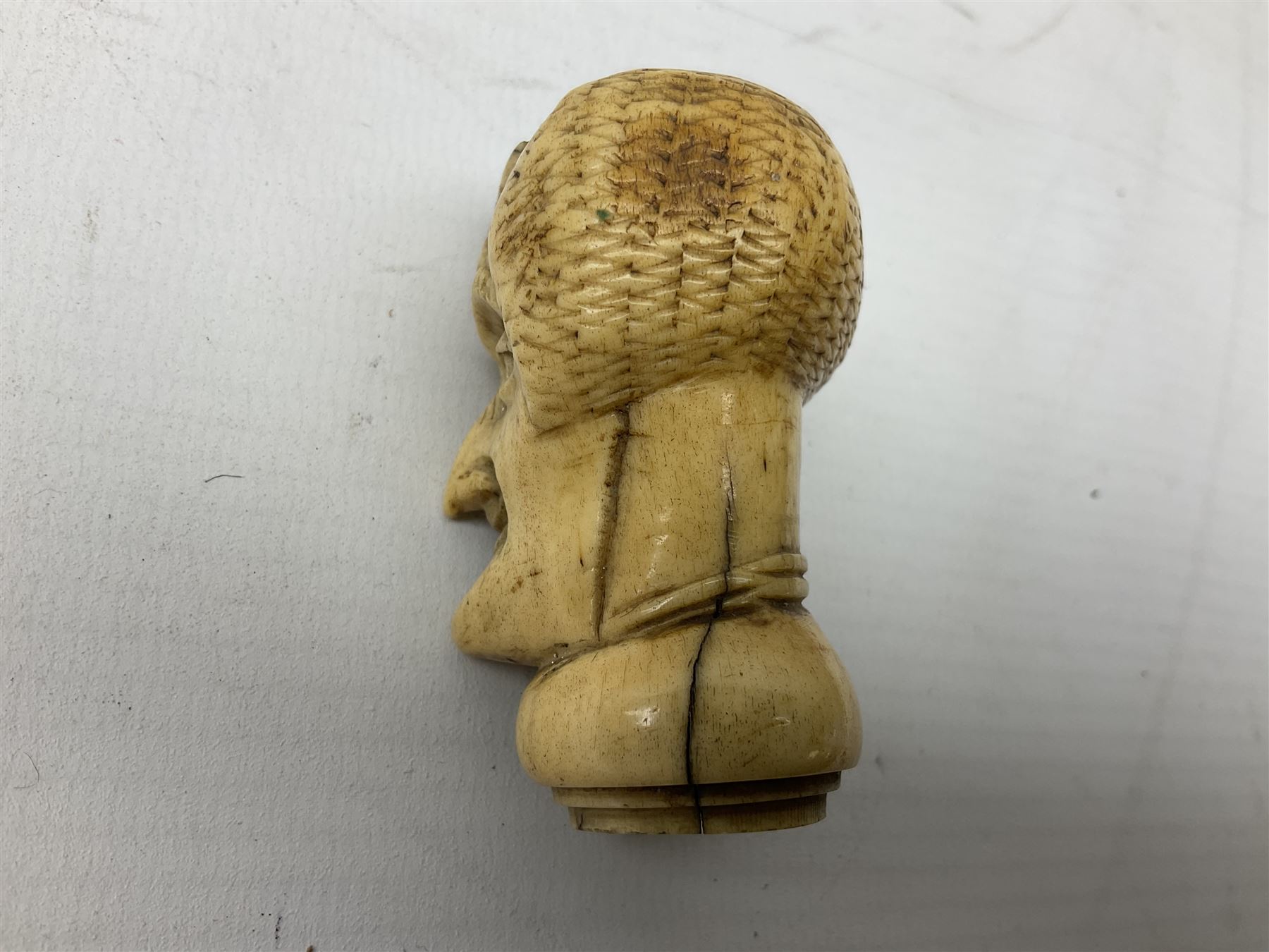 19th century carved ivory walking cane handle, modelled as the head of a greyhound with inset glass eyes, together with a further 19th century ivory example, modelled as a caricature of a gentleman's head, (2)