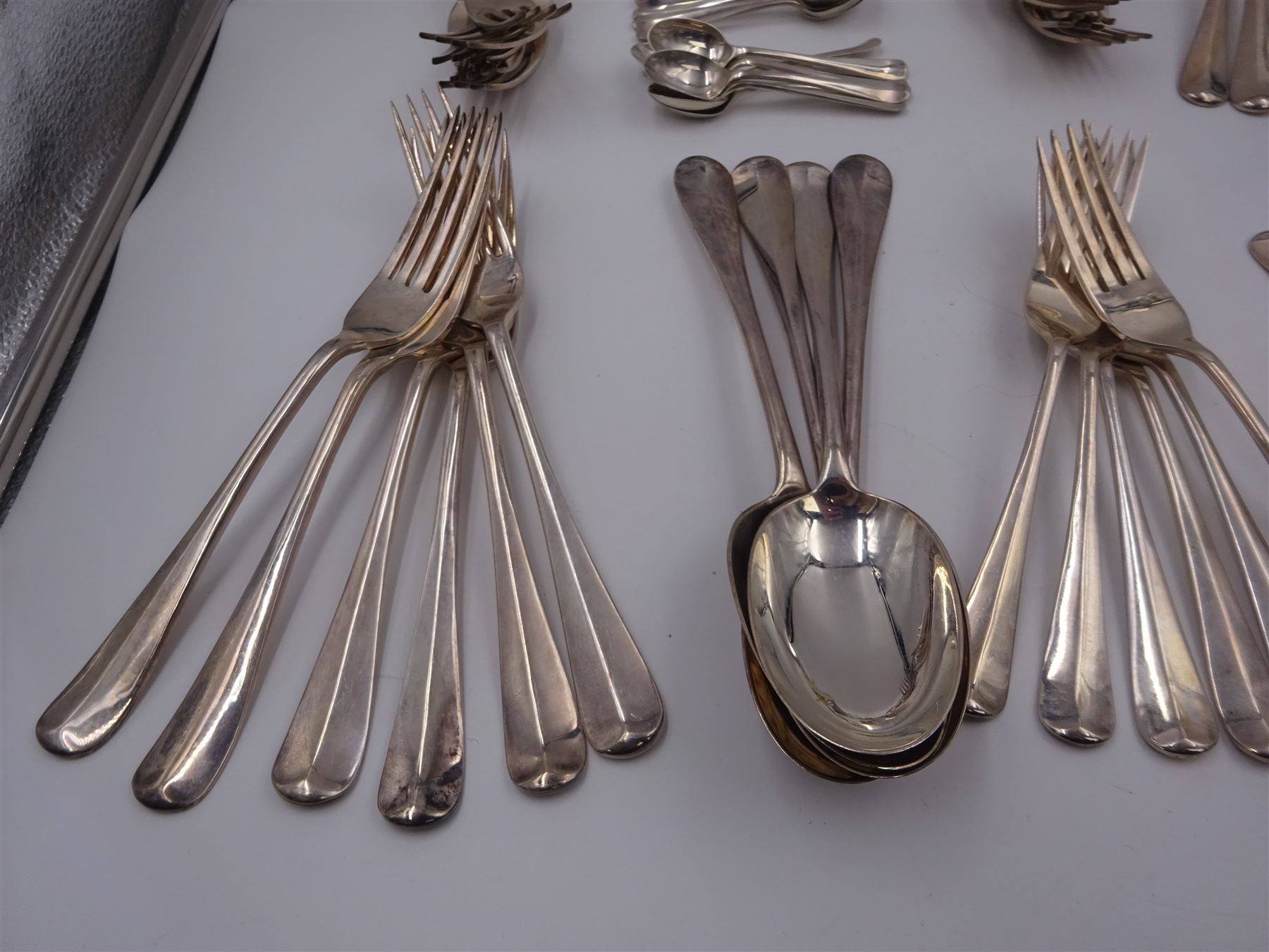 1930s matched set of silver Hanoverian pattern flatware, each with rattail bowls, to include four table spoons, twelve dessert spoons, twelve table forks, twelve dessert forks, twelve teaspoons and twelve coffee spoons, all hallmarked with various makers and dates 