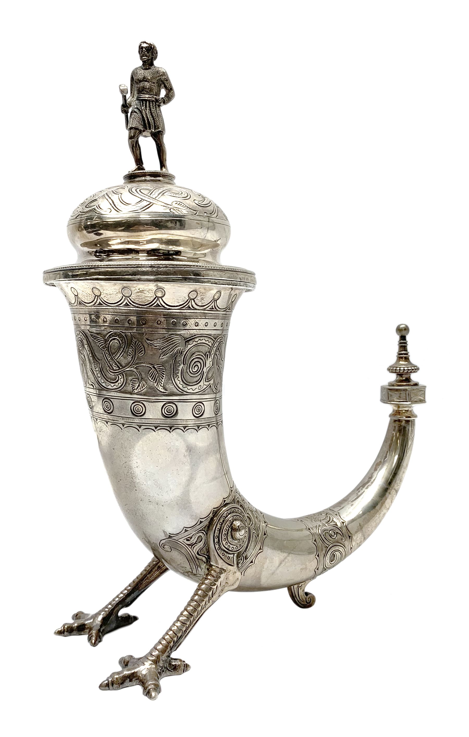 Late 19th century Danish silver drinking horn and cover, the body with hexagonal and beaded finial, raised upon two talon feet and further scroll foot, chased with scrolling foliate and zoomorphic bands, the detachable domed cover with conforming decoration surmounted by a figure holding a hammer, the cover interior impressed with maker's mark (partly worn and indistinct), alongside Danish Three Towers mark for 1881, with the Assay Master mark for Simon Groth (1863-1904), H23.5cm, weight 14.75 ozt (459 grams)

