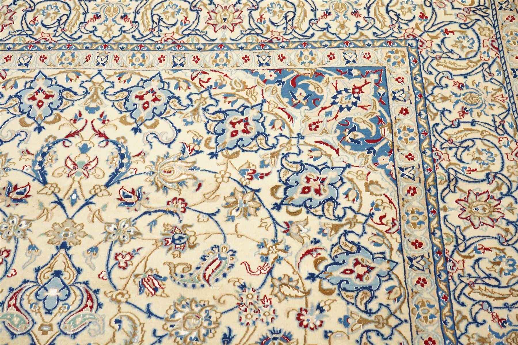 Central Persian Nain hand-knotted carpet, ivory field with central finely drawn cusped medallion of radiating palmette and arabesque form with scrolling vine work, flowering tendrils and stylized foliate motifs in a palette of pale blue, indigo, crimson and sage accents, spandrels of conforming design enclosing intricate floral sprays and arabesques within  multiple borders and narrow guard stripes, with cotton fringe ends 