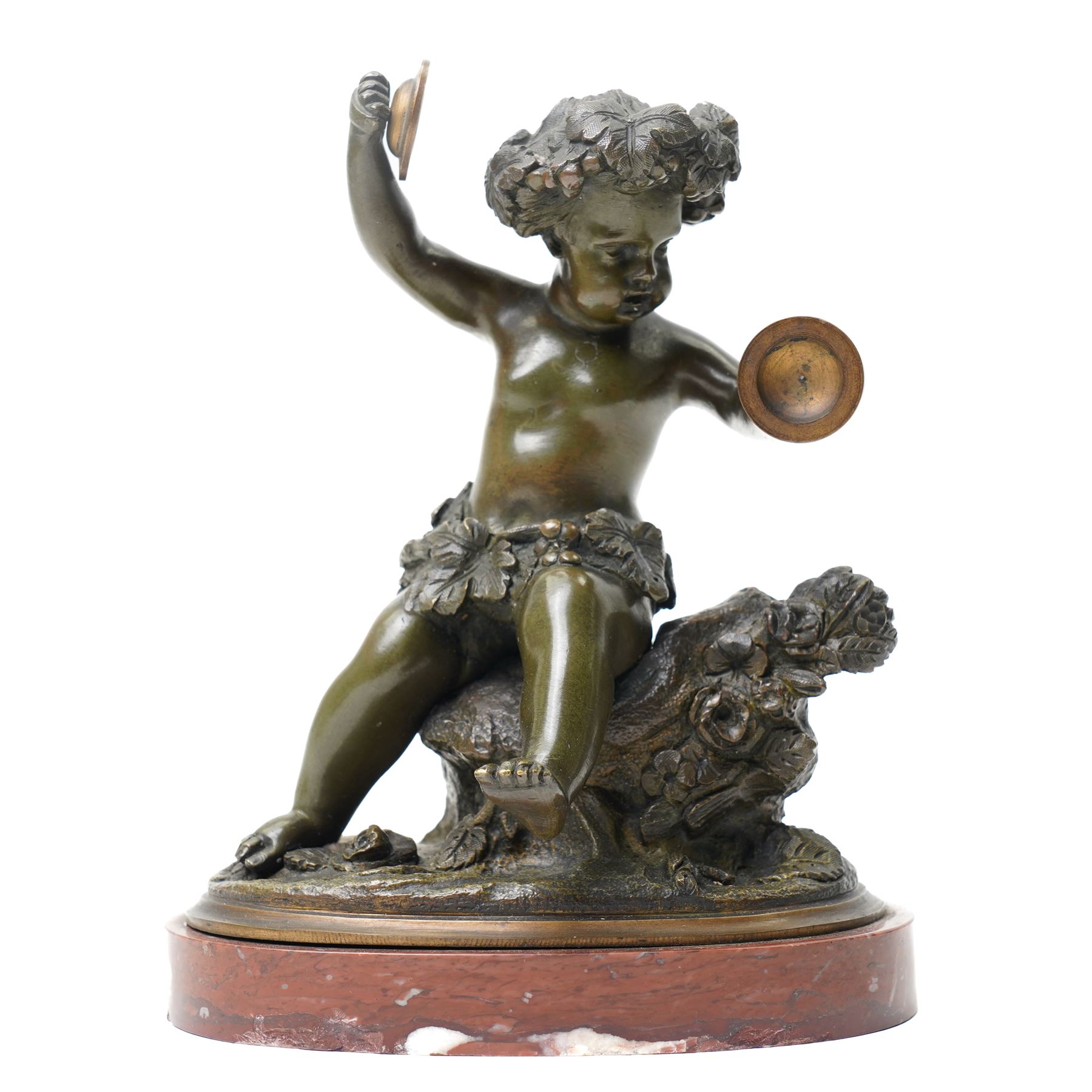 After Michel Claude Clodion (French 1738-1814): Grand Tour patinated bronze figure of a bacchic cherub, modelled dancing and playing cymbals, seated upon a naturalistic rocky base entwined with vine leaves and grapes, bearing signature, mounted on an oval red marble plinth, 19th century, W15cm H19cm