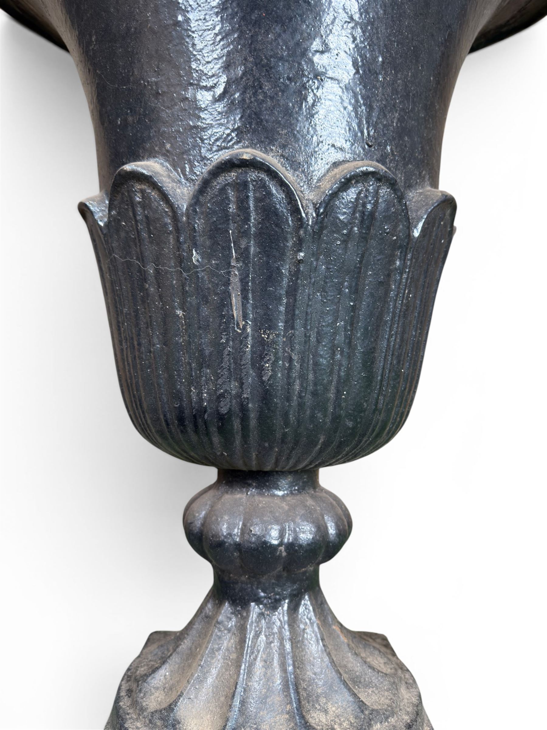 Pair of Victorian large scale cast iron garden urns, flared petal shaped rim with tapering waist, gadrooned base on square plinth, finished in black paint