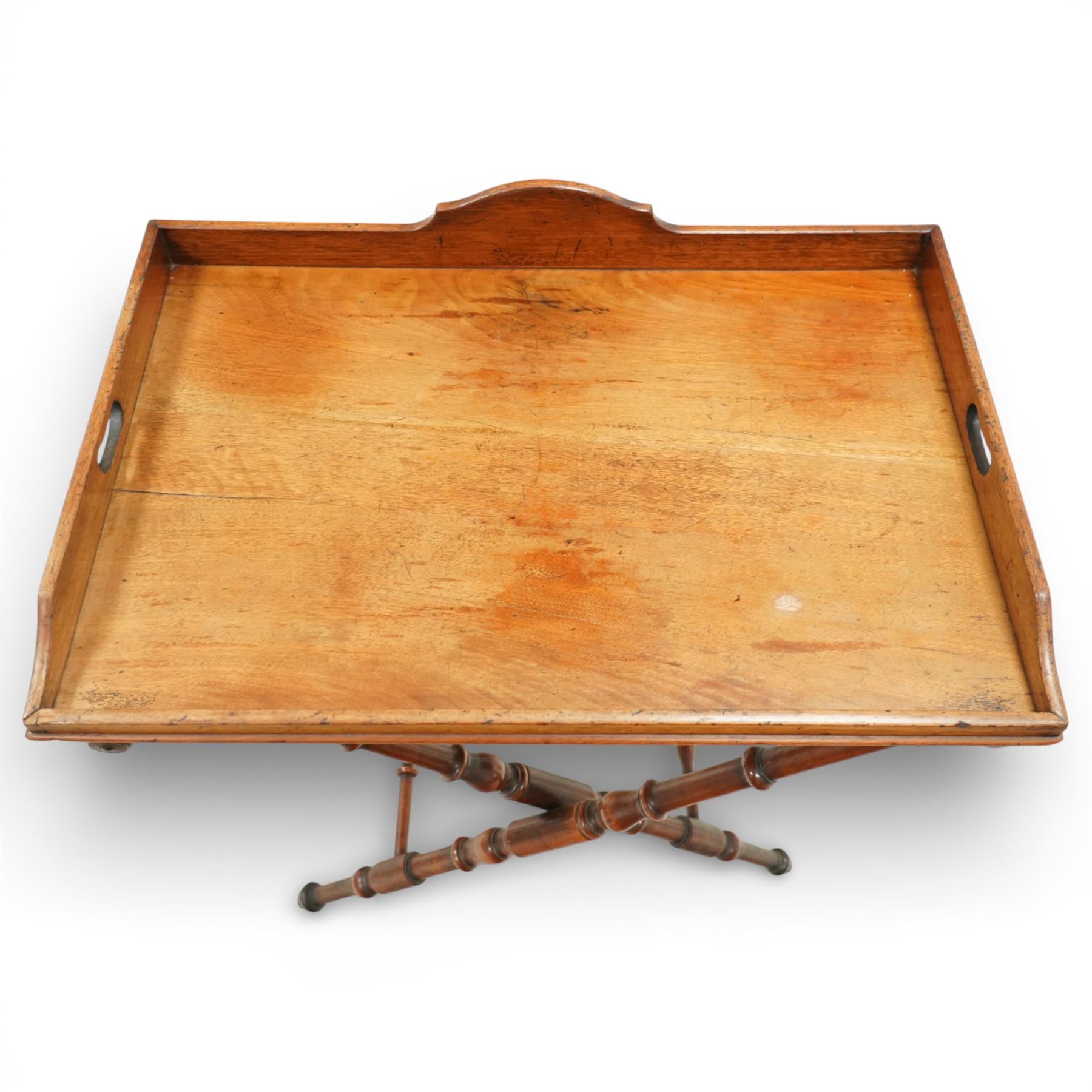 19th century coaching table, the rectangular tray top with shaped gallery and cut out carrying handles, raised on a folding X frame stand with turned supports and stretcher rails