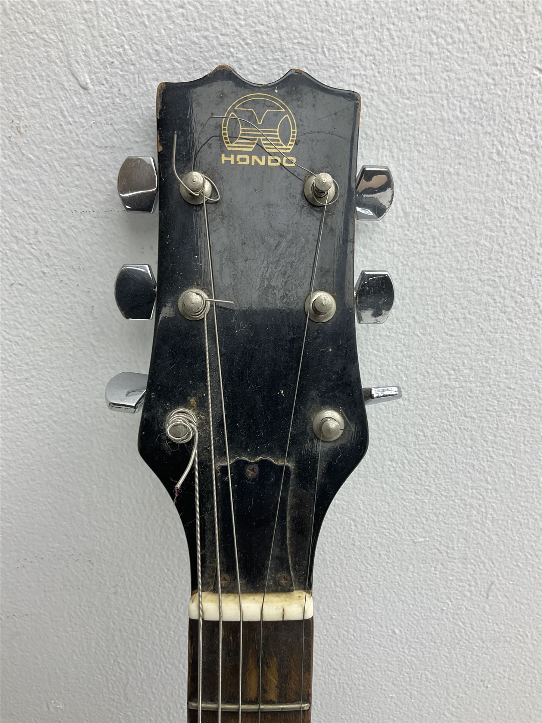 Stagg heavy metal style six-string electric guitar, finished in black with chrome tuning pegs, fret markers and humbucker pickups to bridge L106cm; and Hondo USA electric guitar with black body, ivory coloured pickguard and mother-of-pearl fretmarkers L101cm (2)   