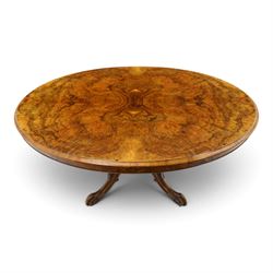 Victorian figured and burr walnut loo table, oval book-matched veneer top with moulded edge, over a turned octagonal pedestal terminating to four splayed supports with flowerhead carved knees and scroll feet with castors