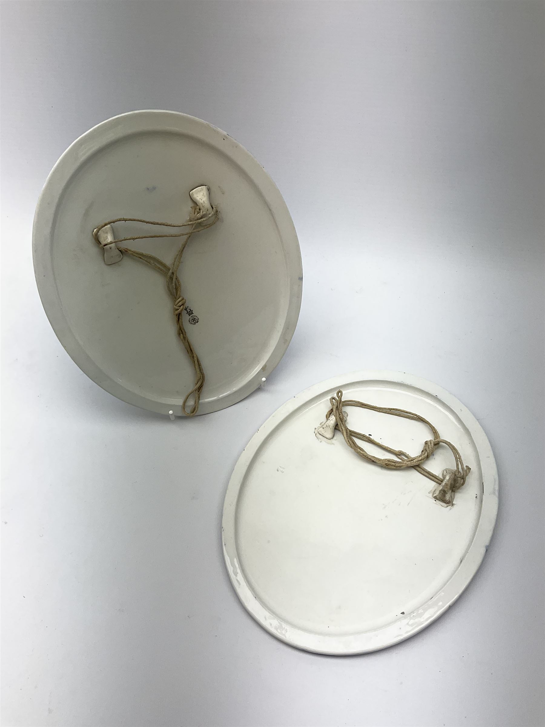 A pair of Royal Doulton blue and white plaques, of oval form decorated with children, one example with printed mark beneath, H24.5cm L19.5cm. 