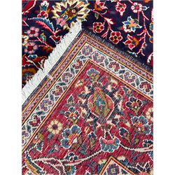Persian indigo ground rug, the central crimson pole lozenge medallion surrounded by interlacing floral patterns, the main border with repeating plant motifs connected by scrolling branches