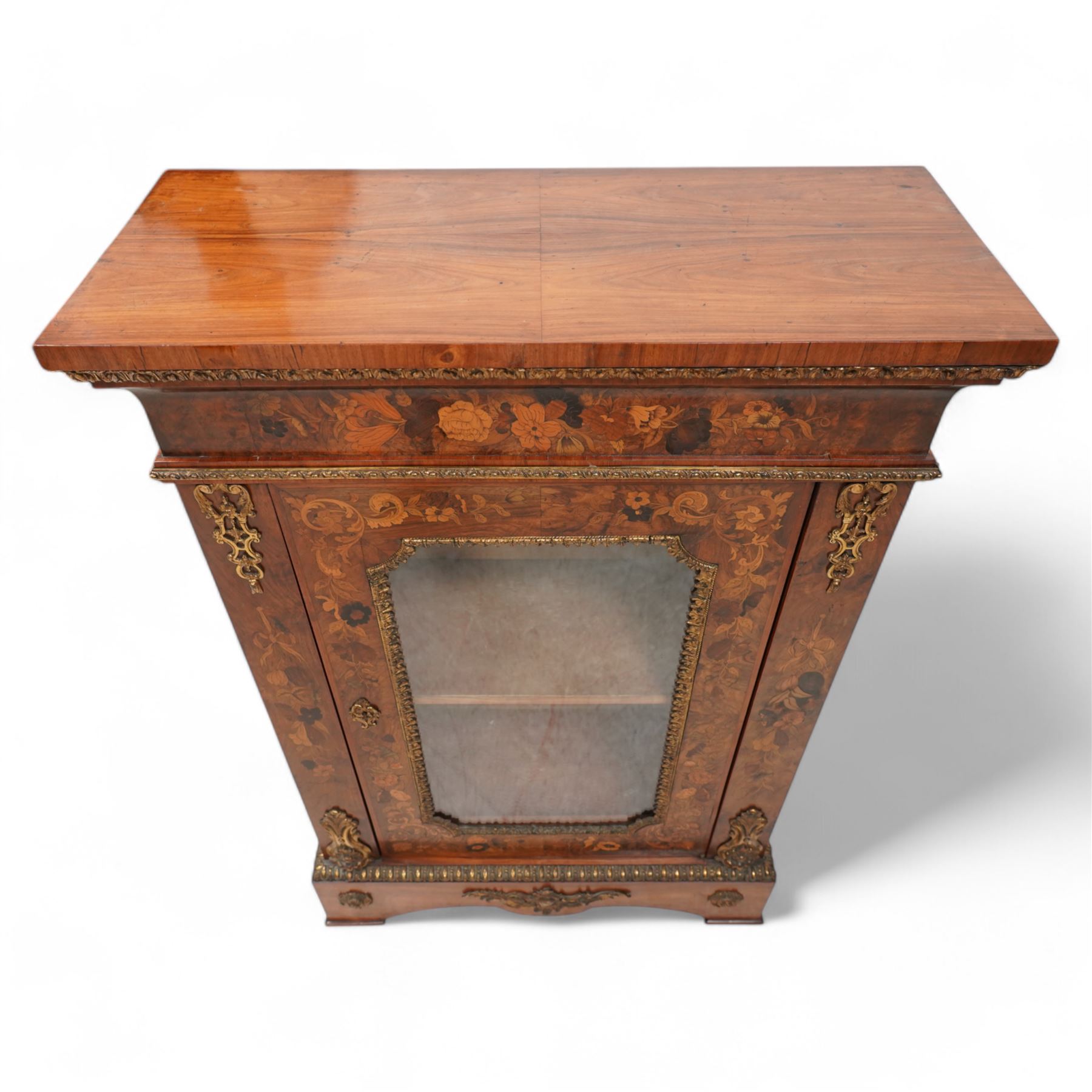 Victorian walnut and gilt metal mounted pier cabinet, rectangular top over acanthus leaf moulded gilt metal edging and floral inlaid frieze, single glazed door inlaid with scrolling leafage and flower heads, fitted with single internal shelf, egg and dart moulded lower edge over shaped skirt base 