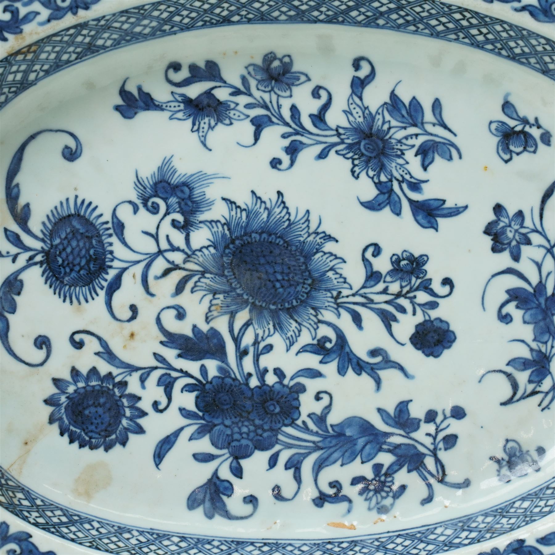 18th century Chinese oval dish shallow dish decorated with flowers in blue and white within a scroll and key pattern border W37cm and a Chinese blue and white charger D34cm (2)