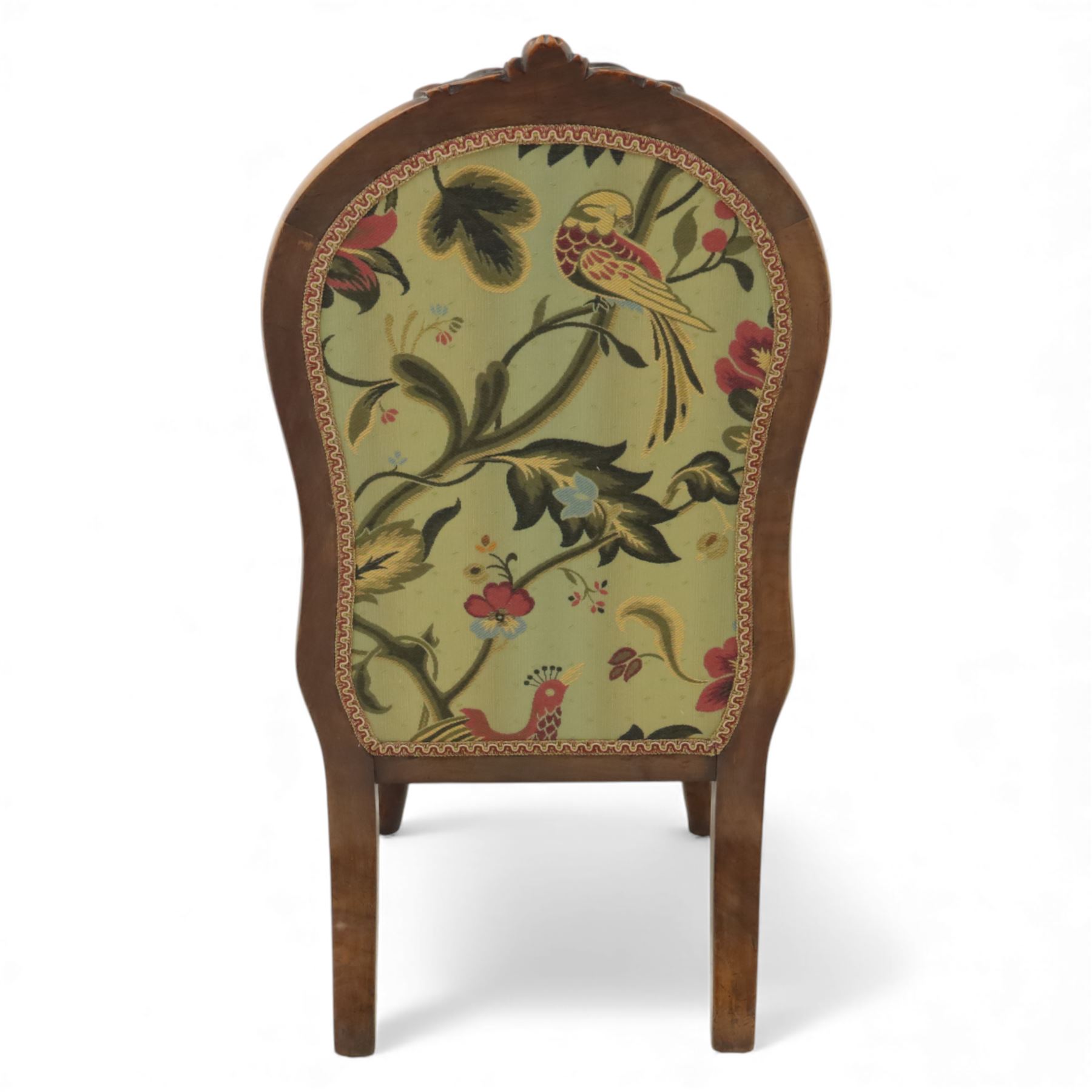 Small Victorian mahogany nursing chair, with carved top rail above a padded balloon back and shaped seat upholstered in light green fabric detailed with exotic birds and flowering vines, raised upon cabriole front legs and turned rear supports