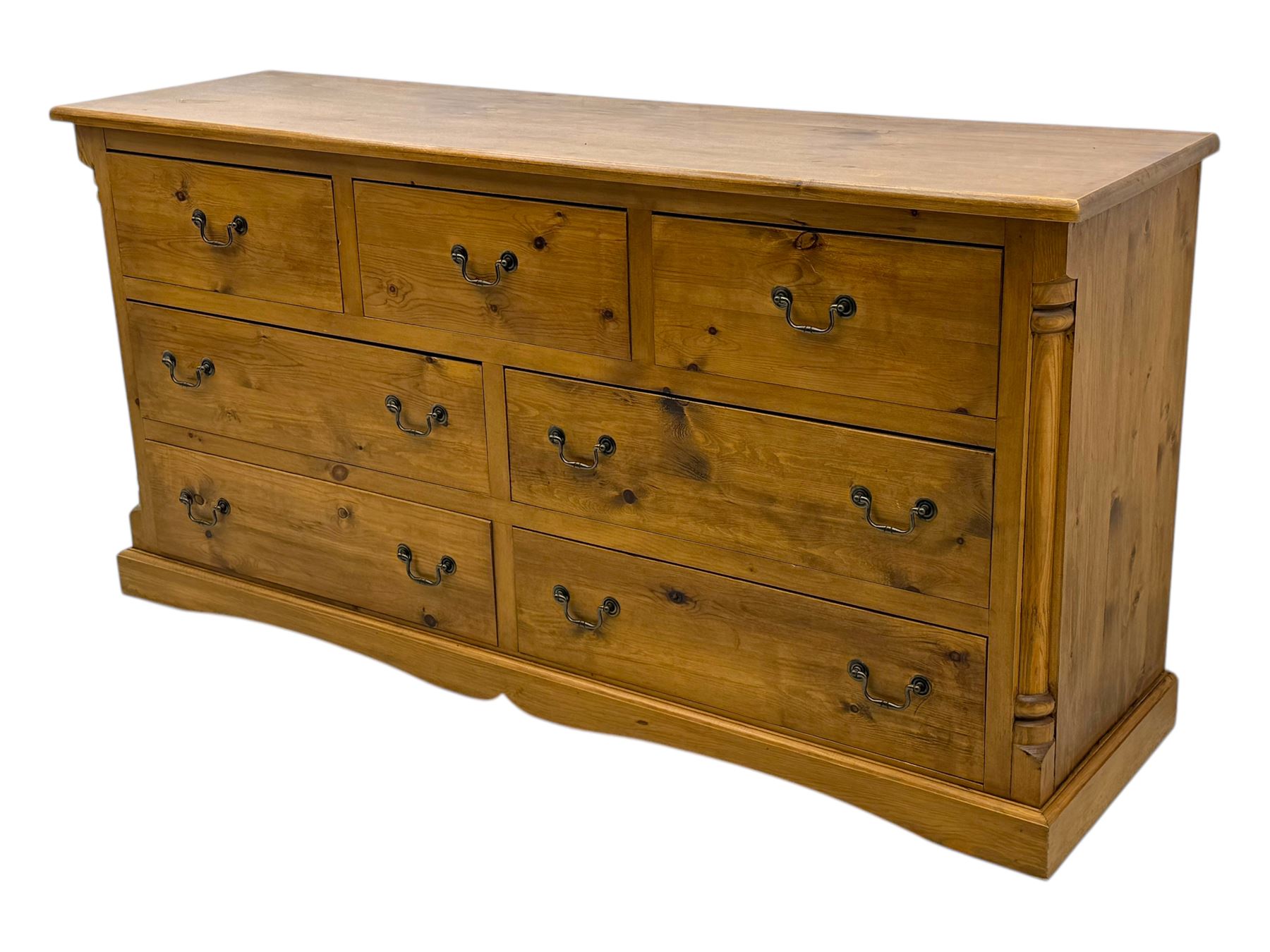 Pine dresser, rectangular top above seven drawers, with two smaller drawers over five larger drawers, all fitted with cast metal handles, raised on a shaped plinth base


