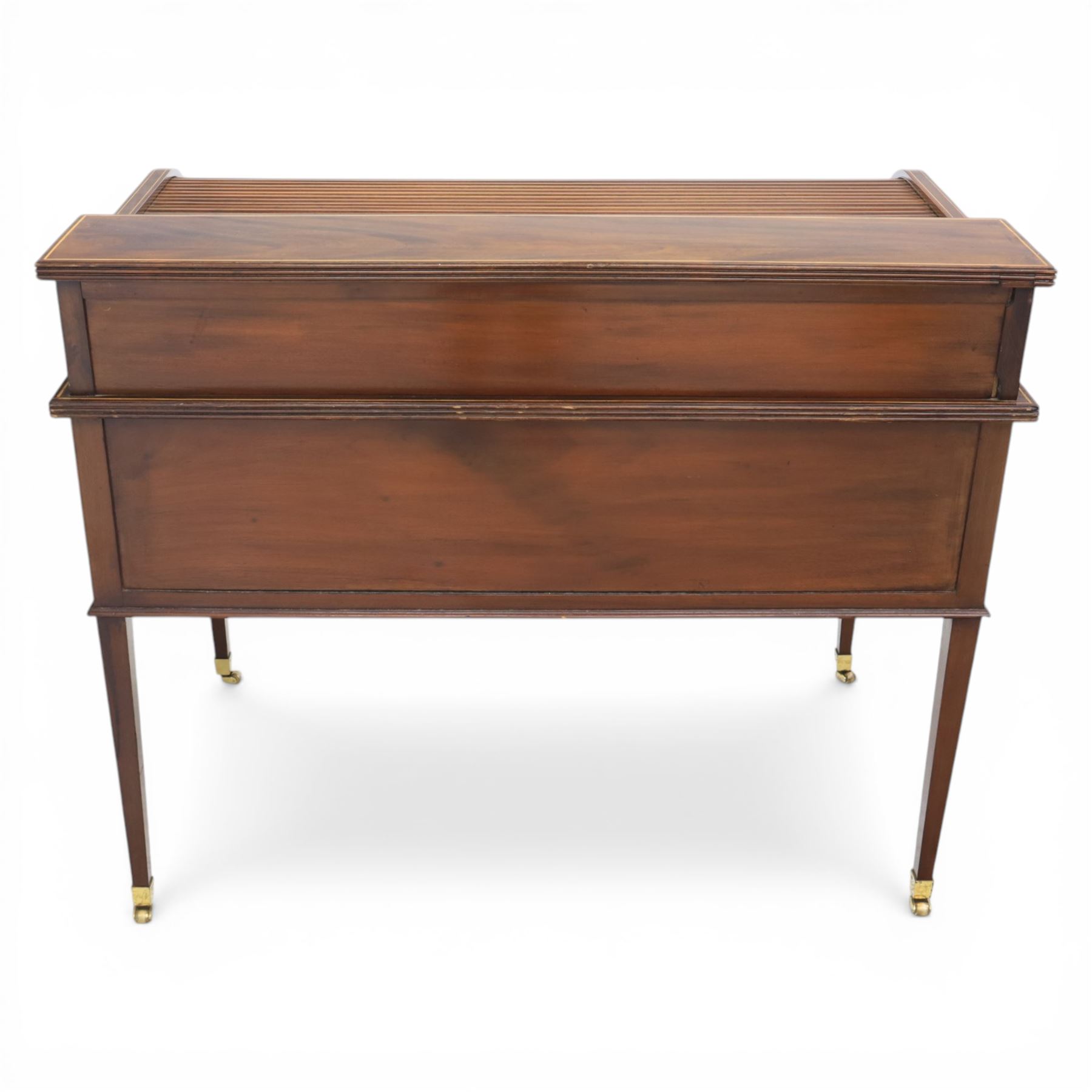George III style inlaid mahogany tambour desk, the roll top enclosing fitted interior with small drawers and compartments above inset leather writing surface, over three frieze drawers, raised on square tapering supports with brass caps and castors