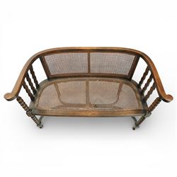 20th century bergère two seater settee, with shaped curved top rail and downswept arms, the back and seat fitted with woven cane panels, supported by turned uprights and legs united by a carolean stretcher 