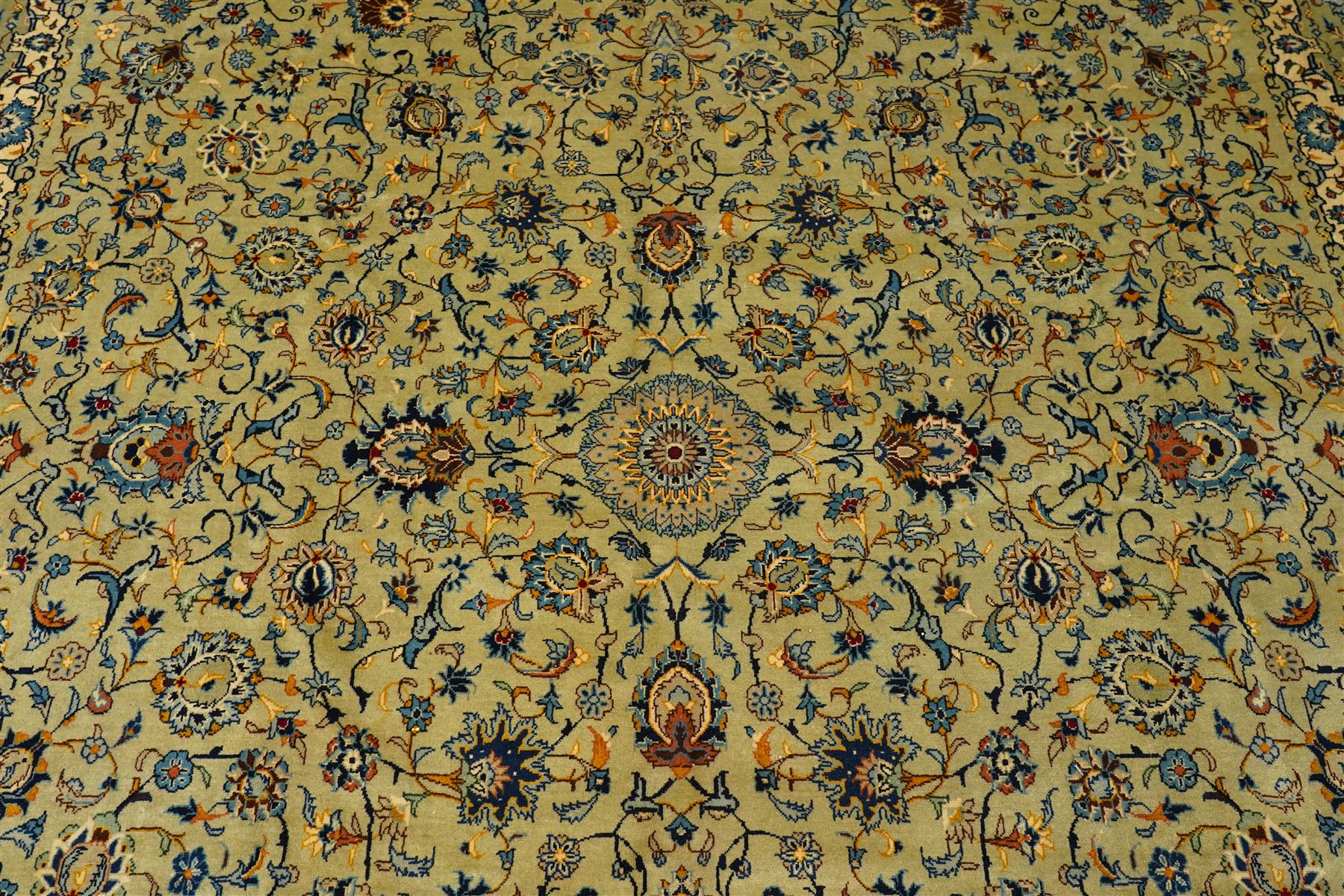 Central Persian Kashan hand-knotted carpet, pale blue field decorated with a finely drawn all-over scrolling floral vine design incorporating stylized palmettes, rosettes and foliate sprays, with a small central circular medallion, enclosed by a conforming floral vine border between multiple guard stripes, with cotton fringe ends  
