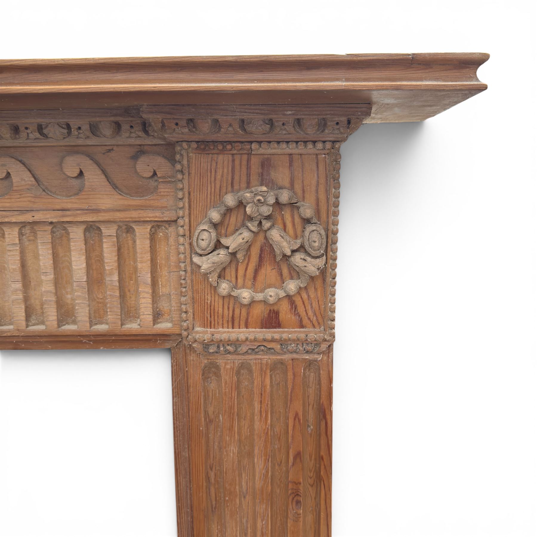 19th century Adams design pine fire surround, egg-and-dart carving over Vitruvian scrolls and fluted frieze, decorated with applied carved festoons and garlands, on fluted uprights