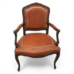 Pair of late 20th century French style carved beech open armchairs, the shaped and moulded frames with foliate cresting rail above padded backs and overstuffed seats upholstered in tan leather with gilt foliate borders and close nailed trim, raised upon cabriole supports with acanthus carved knees