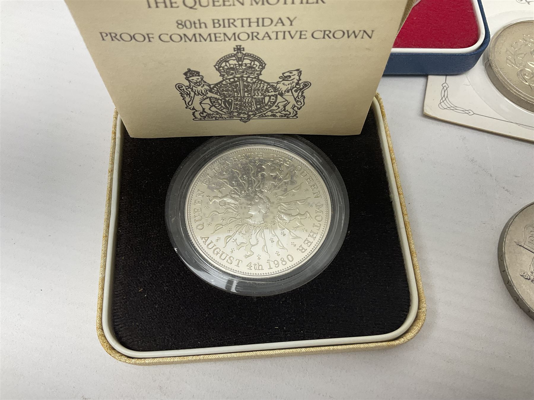 Queen Elizabeth II 1977 silver crown and 1980 silver crown, both cased with certificates, Bailiwick of Guernsey 1978 silver crown cased without certificate, three United Kingdom brilliant uncirculated five pound coins in card folders and twelve other five pound coins