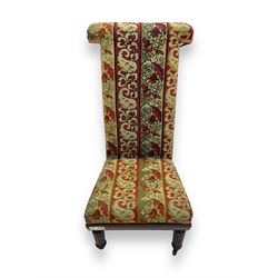 19th century mahogany framed prie-dieu chair, upholstered in red and green patterned fabric, high back with rolled top, standing on turned front supports with castors