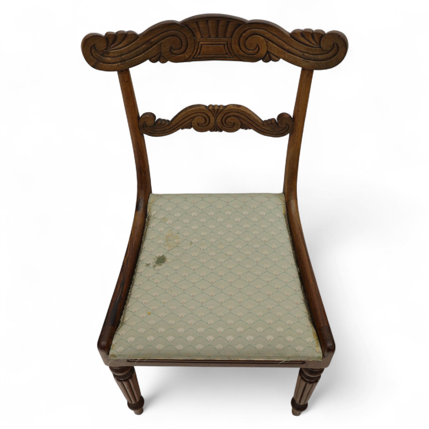 Set of four 19th-century rosewood dining chairs in the William IV style, shaped and carved top rail with fan and scroll decoration above a upholstered padded seat on reeded and turned front legs 