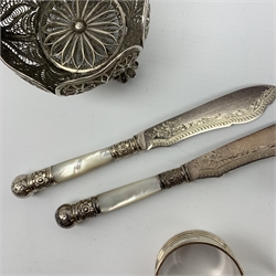 An unmarked silver filigree bon bon dish, D7.5cm, (a/f), together with two silver napkin rings, hallmarked Joseph Gloster Ltd, Birmingham 1959, and John Rose, Birmingham 1953, and a mother of pearl and silver plated pair of knife rests and knifes. 
