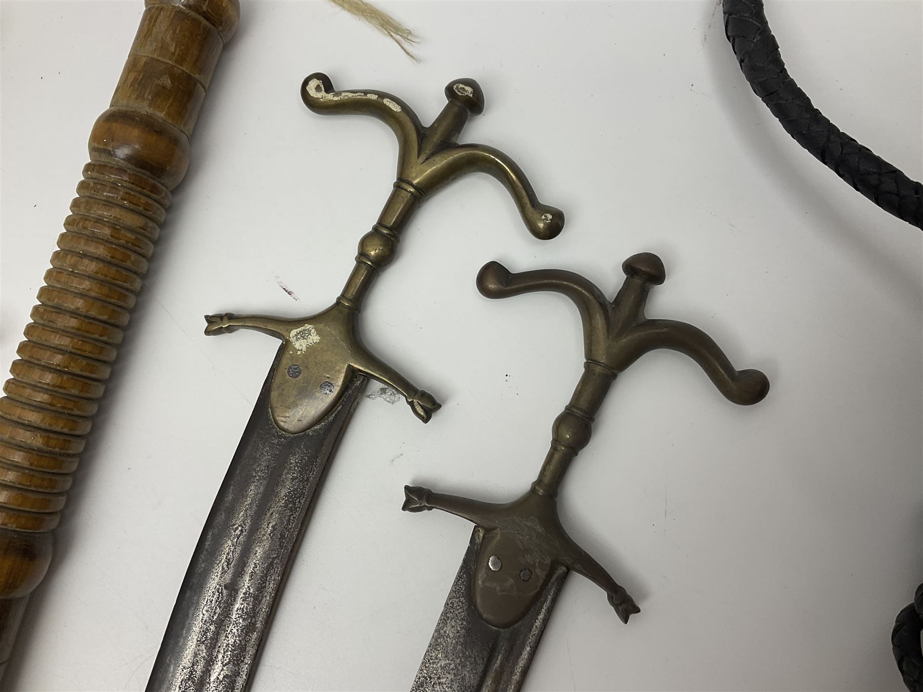 Near pair of short swords each with slightly curving 41cm fullered steel blade and all brass H-shaped hilt L52cm overall; plaited black leather whip; and reproduction pair of brass hilted swords, brass halberd blade and mace (7)