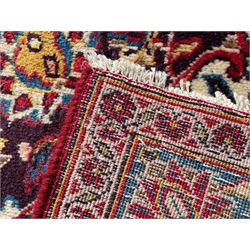 Large Persian Kashan crimson ground carpet, large floral central medallion surrounded by trailing branches decorated with leaves and stylised plant motifs, the main border with scrolling design interspersed with palmettes, within floral pattern guard stripes 