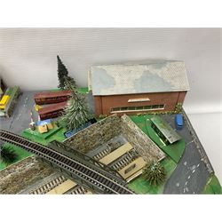 Table top 'N' gauge continental scenic layout as a split level town with various loops of track, station with numerous platforms, engine shed, assorted buildings, roads with motor vehicles and figures, tunnels, trees, river with bridge, tram depot etc 122 x 52cm