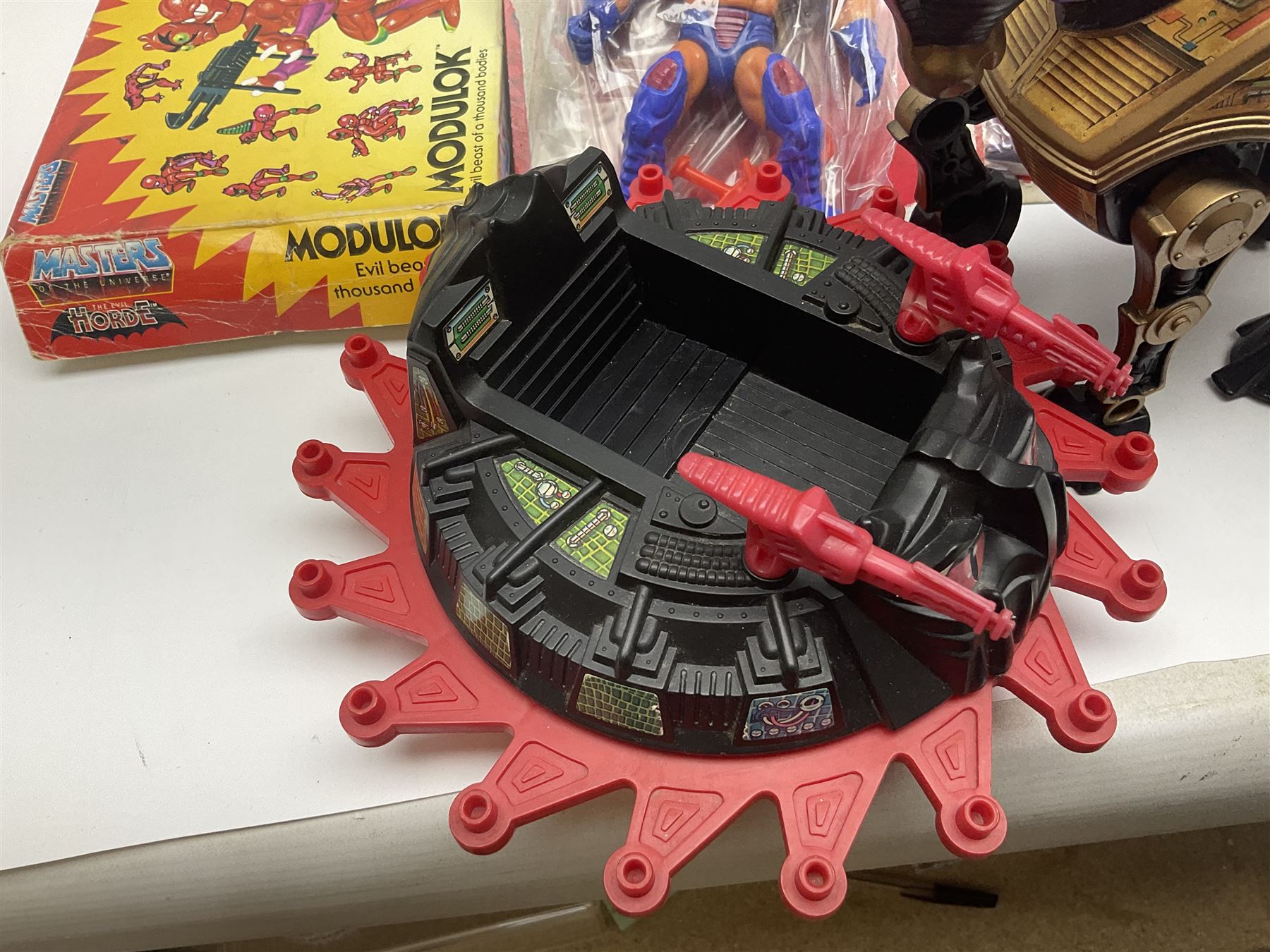 Thirty-one Masters of the Universe He-Man figures re-bagged on original backing cards;  two others lacking backing cards; boxed Modulok figure; bag of weapons and accessories; Roton, two horses and two battle cats; 1986 & 1987 Annuals; Ladybird and other story books; Panini sticker album; instructions etc