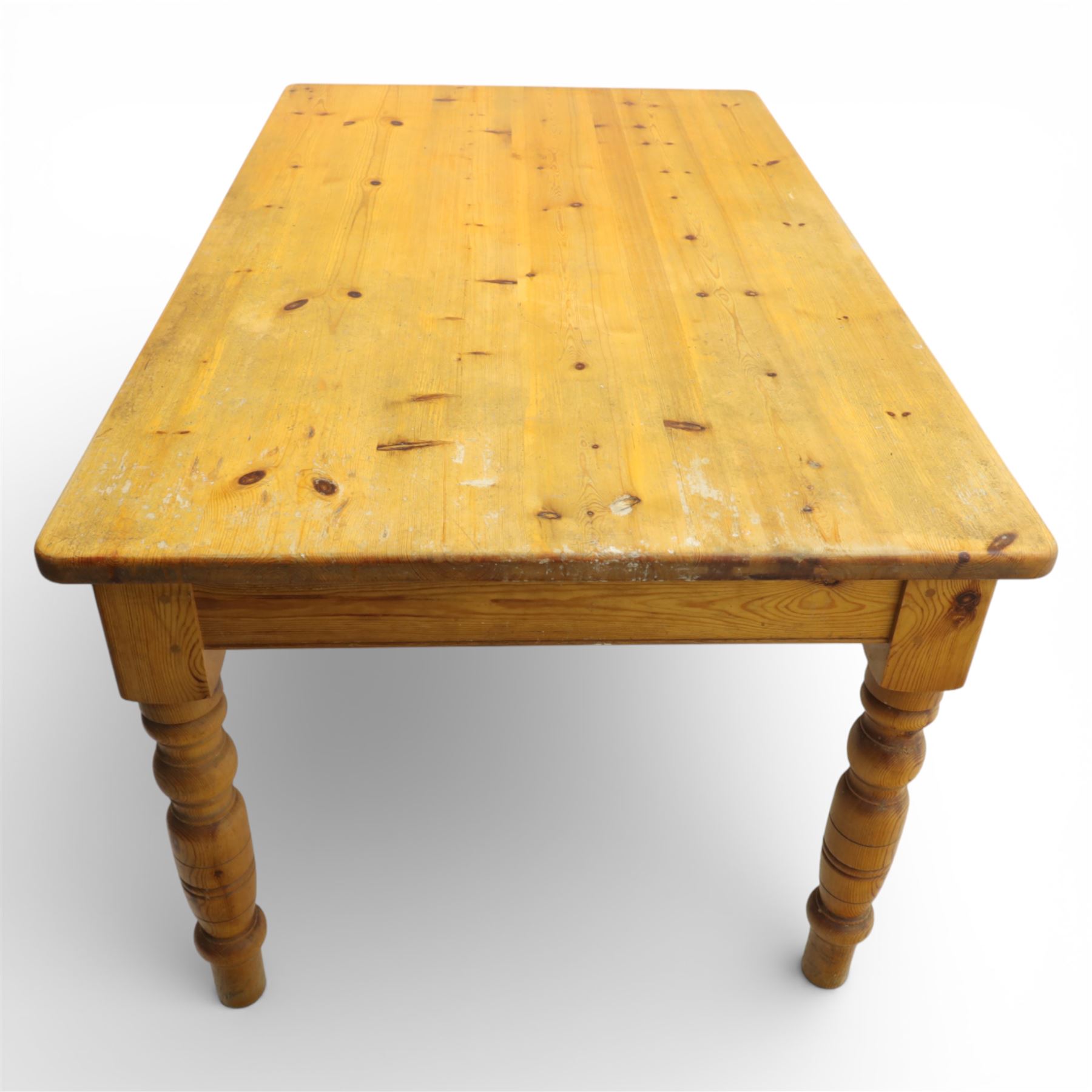 Late 20th century pine farmhouse dining table and four chairs, the rectangular plank top with rounded corners over two frieze drawers fitted with turned knob handles, raised on turned legs, the chairs with shaped ladder backs and turned finials, rush seats in a herringbone weave, on turned supports united by stretchers