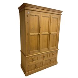 Pine triple wardrobe, enclosed by three panelled doors, fitted with five drawers, on skirted base