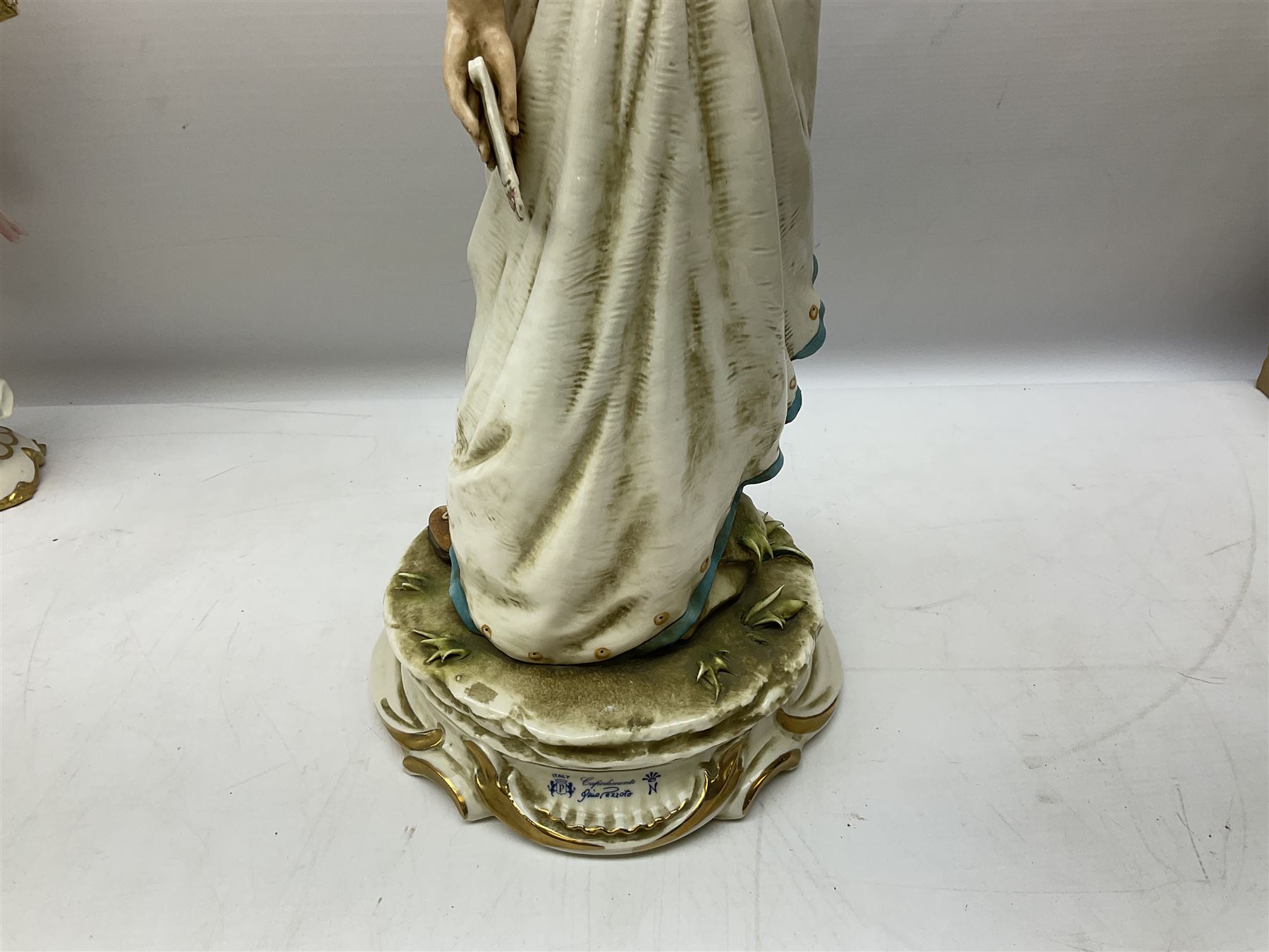 Pair of Capodimonte table lamps, in the form of cherubs holding a brass fitting, together with a pair of large Capodimonte figures in the form or a man and woman resting up on tree stump, largest example H57cm