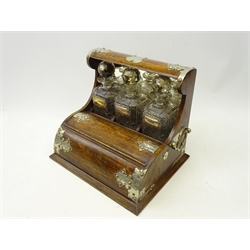  Early 20th century oak roll top tantalus, the three cut glass decanters with faceted stoppers and mirrored panel behind, silver-plated labels for 'Port', 'Brandy' and 'Sherry', silver-plated mounts with side carrying handles and lift-out interior containing cribbage board, W36cm, D28.5cm, H30.5cm  