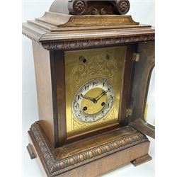 Early 20th century eight-day Junghens quarterly chiming mantle clock, two train movement with supplementary chiming train, chiming on 5 gong rods, brass dial plate with engraved detail and silvered chapter ring with upright Arabic’s and minute track, fleur di Lis steel hands, walnut case on raised corner feet, plinth with egg and dart moulding, arched glazed door with reeded columns and capitals, broad moulded cornice surmounted by a stepped pediment and semi-circular recessed carving with rosettes. 
With key and Pendulum.
