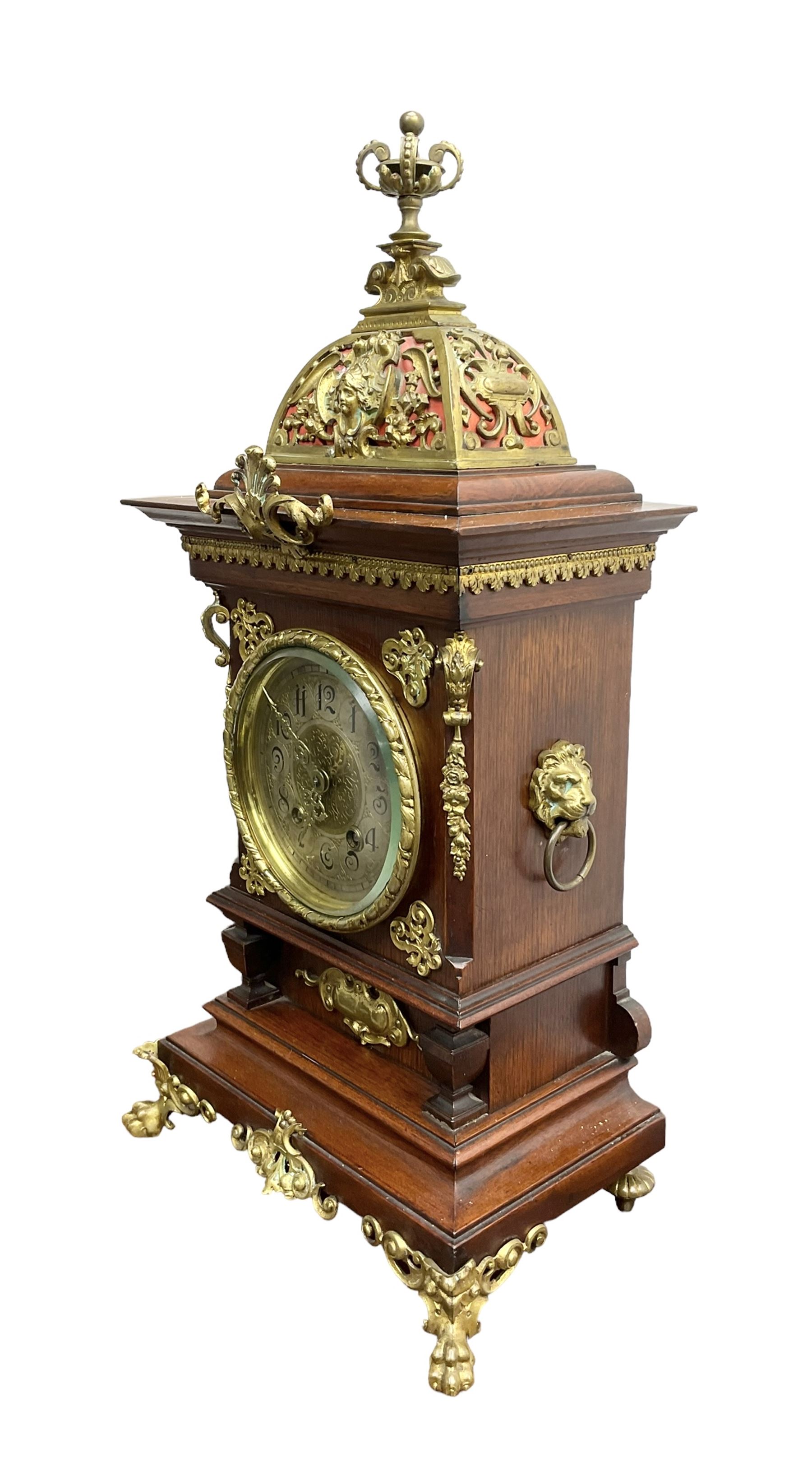 Lenzkirch - Edwardian German 8-day  mantle clock in an oak case with brass mounts and a pierced dome pediment with finial, silvered dial with Arabic numerals, gilt hands and dial centre, rack striking movement, striking the hours and half-hours on a coiled gong. With pendulum and key.