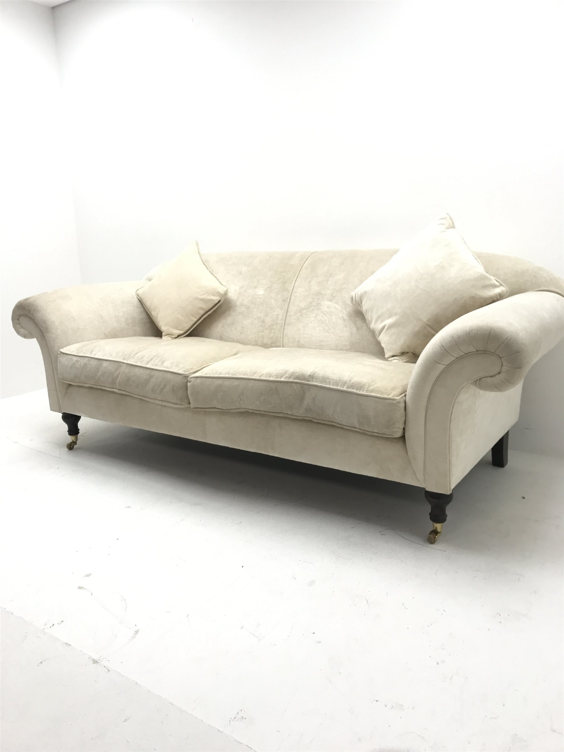 Three seat sofa upholstered in an cream chenille fabric, scrolled arms, turned supports, W220cm