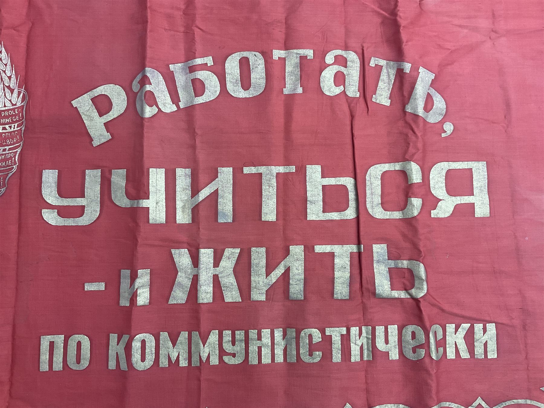 1970s Soviet banner printed in gold on a red ground, roughly translates as 'Transferable Banner - To the winner in the Socialist Competition' and 'Work Study Live by Communism' verso; wreath of wheat ears to either side; tassels on three sides 110 x 155cm