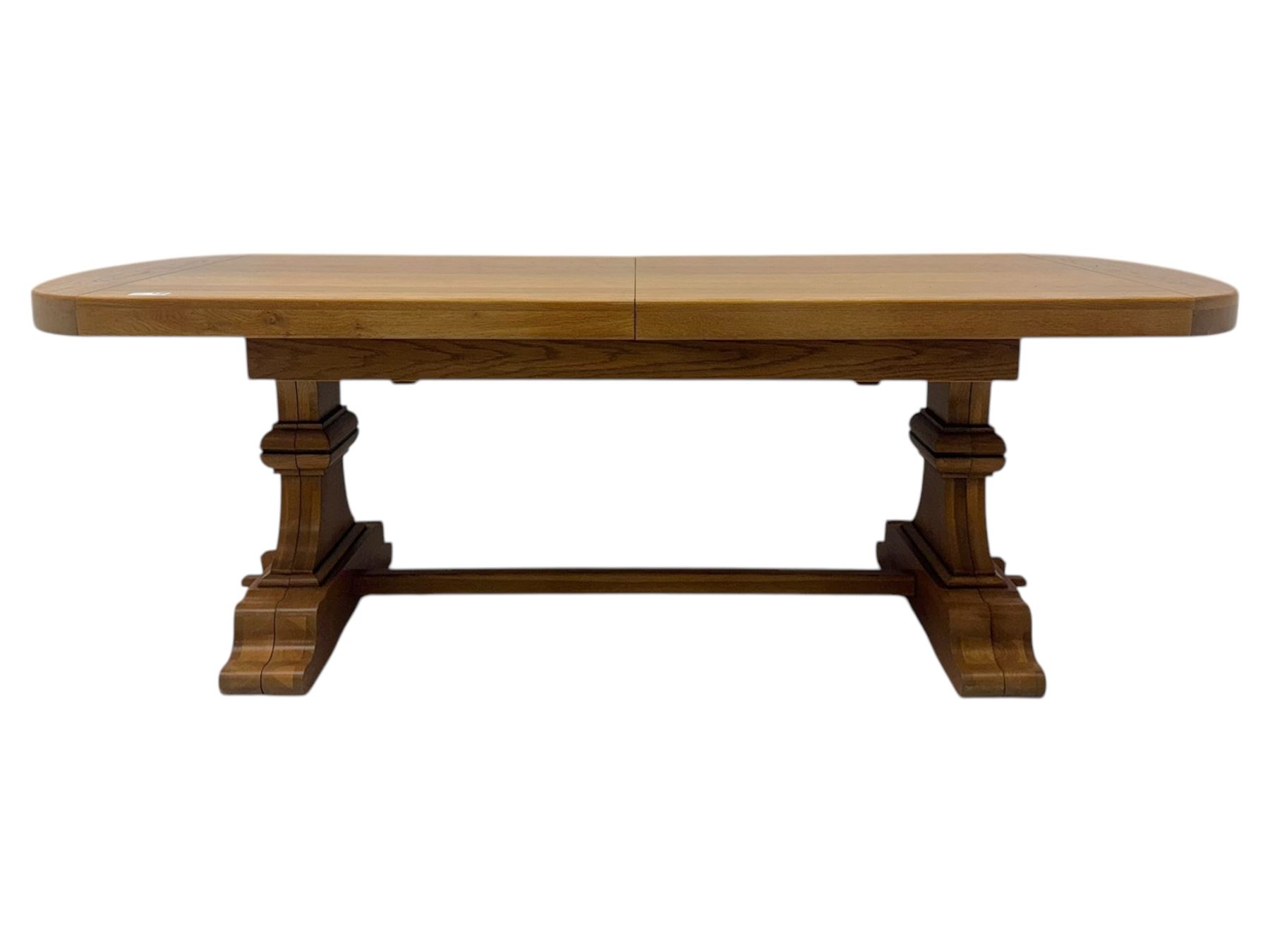 Oak extending dining table with elegant scrolled shaped double pedestal base and scrolled feet; together with a set of eight ladder back chairs with rush seats ((9) table closed 228x95x79cm chairs 106x38x44cm 