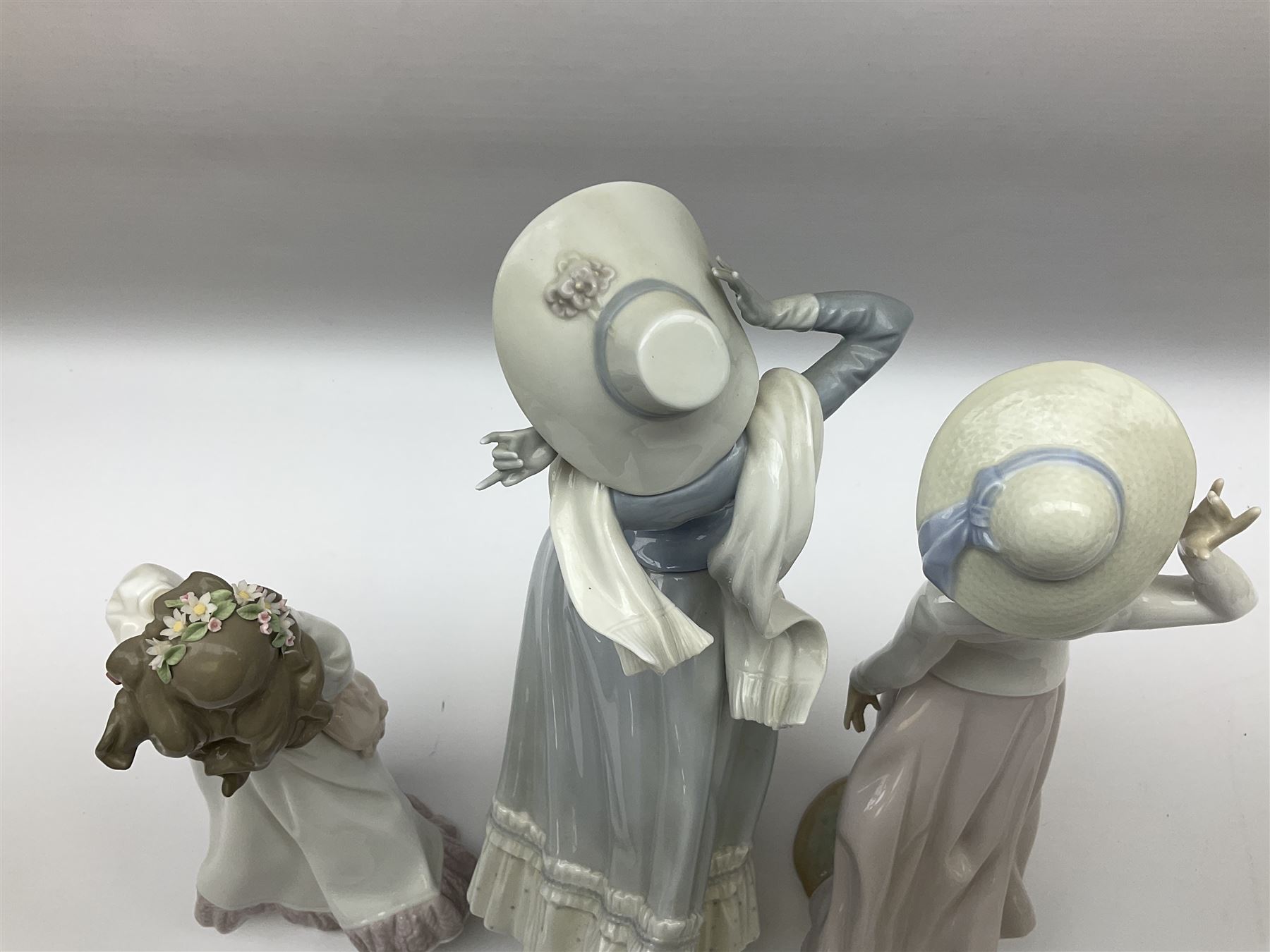Three Lladro figures, comprising, Dreams of Summer Past no 6401, Spring Breeze no 4936 and Breezy Afternoon 5682 together with Lladro plaque Art Brings us Together no 7677, all in original boxes, largest example H35cm
