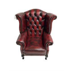 Queen Anne design wingback armchair, scrolled back and arms, upholstered in buttoned oxblood leather with studwork border, raised on cabriole supports