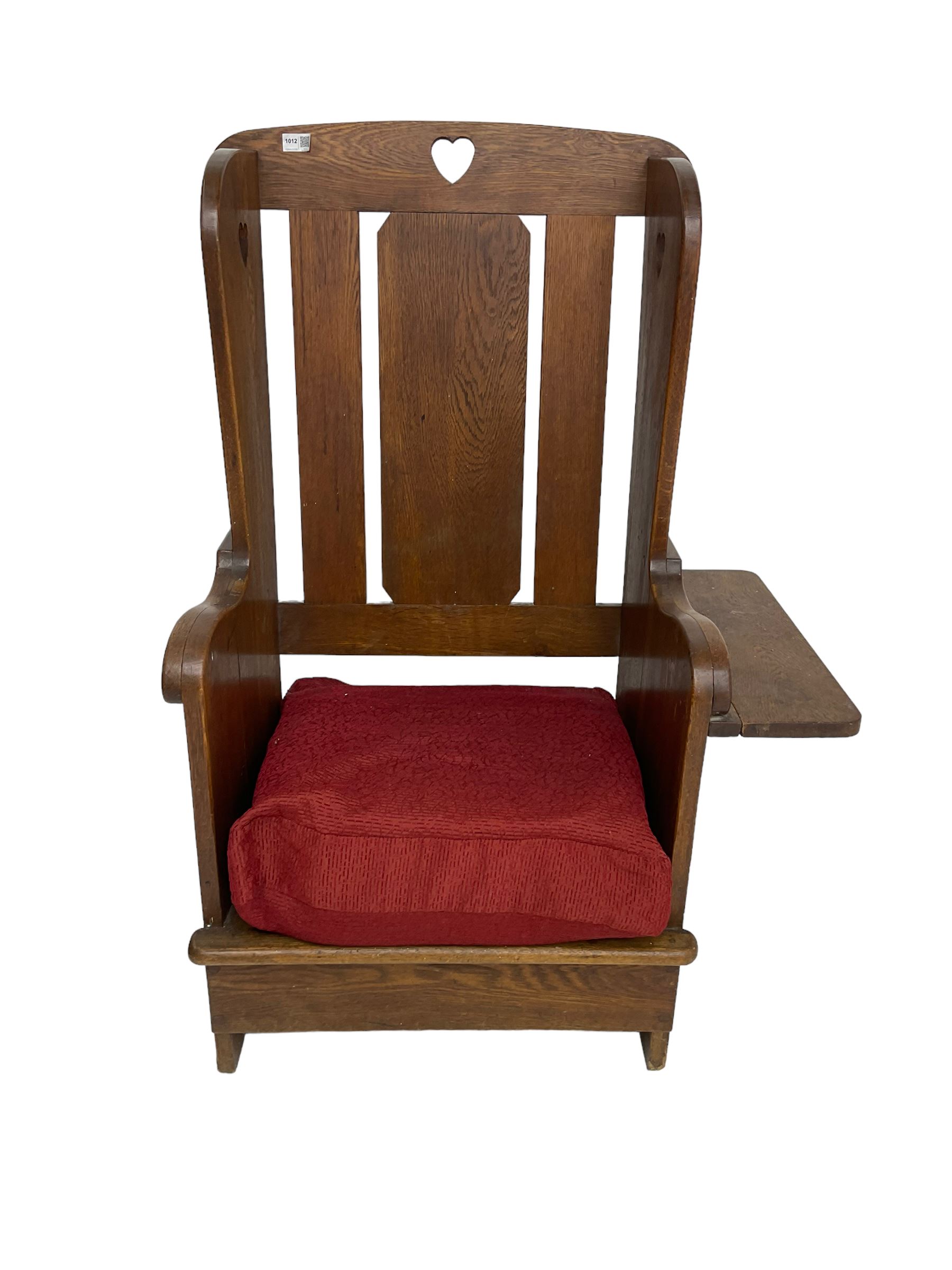 Arts and Crafts design oak reading wingback armchair, high back with pierced heart design, drop-leaf side table to one arm