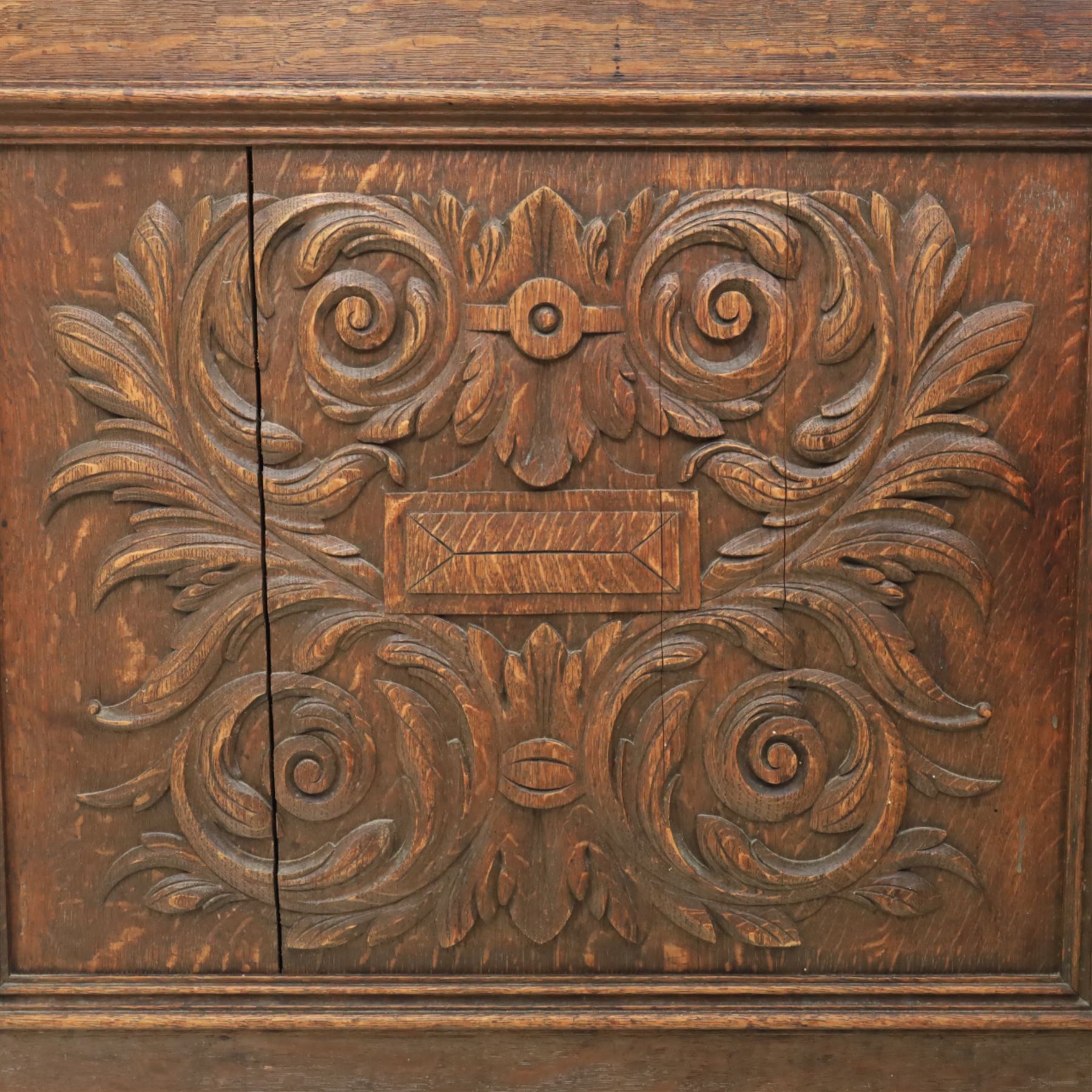 Victorian carved oak sideboard, the rectangular top with raised back carved with foliate scrolls and scroll end supports, upon a base with rectangular top with moulded edge, pair of drawers with conforming carved decoration and mask handles, and pair of carved cupboard doors, upon short stile type feet H101.5cm W183cm D54cm 