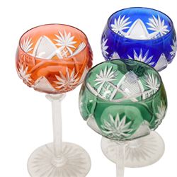 Set of six 20th Century Val St Lambert Berncastel style crystal glass wine glasses, in yellow, greens, red, purple and blue, flash cut with a repeat diamond and plume pattern above a knopped cut stem and circular spread foot, H18cm